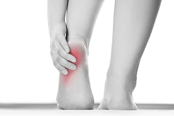 Person gripping heel with hand showing redness indicating pain or inflammation