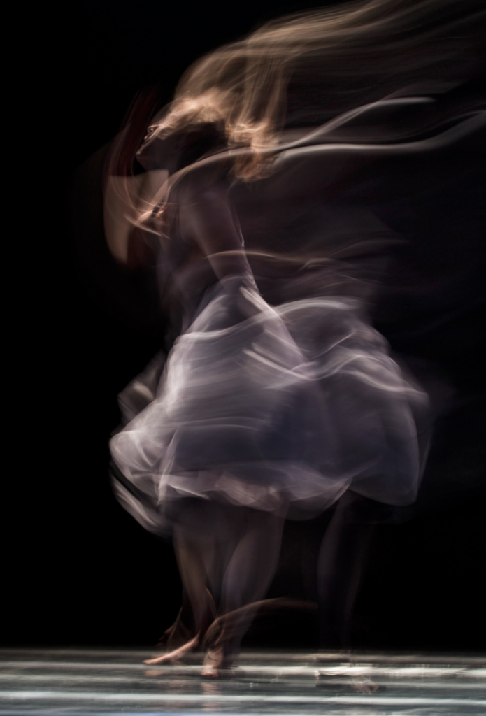 Dancer performing on stage with bare feet and flowing skirt