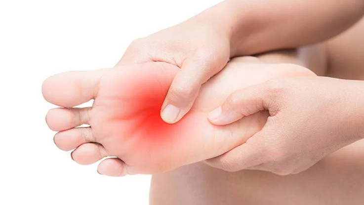 Person holding the sole of their foot with highlighted red pain area indicating neuropathy