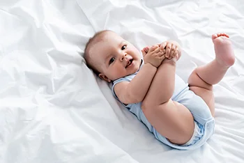 Baby lying on back holding both feet up with hands