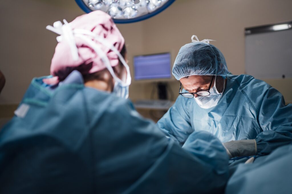 Two surgeons in scrubs and masks performing a foot surgery in an operating room