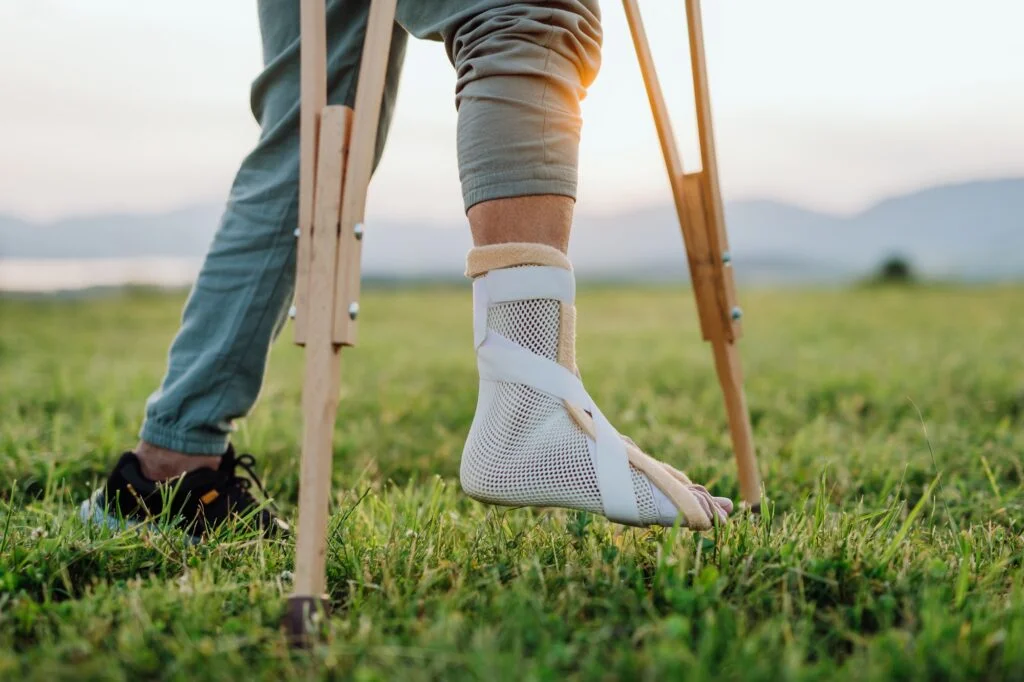 Person wearing an ankle brace and using crutches.